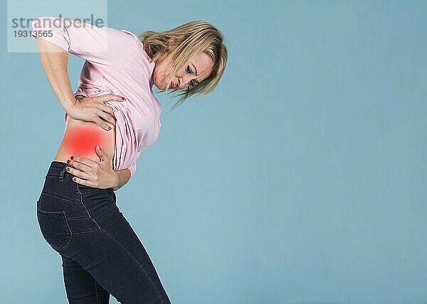 Stressige Frau mit Schmerzen im unteren Rückenbereich blaür Hintergrund