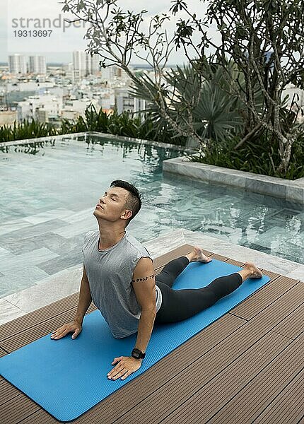 Mann macht Yoga am Pool