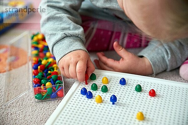 Kleinkind spielt mit bunten Stiften