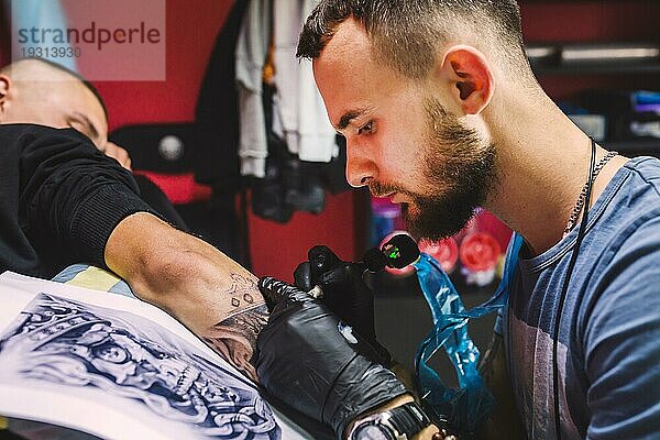 Erwachsener Mann arbeitet mit Tattoo Stift Arm