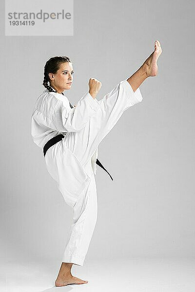 Junge erwachsene Frau mit schwarzem Gürtel  die Karate trainiert