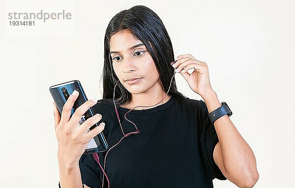 Latin Girl genießt Musik mit Telefon isoliert. Porträt des schönen Mädchens hören Musik mit Smartphone isoliert. Glückliche lateinische Mädchen hören Musik mit Handy isoliert