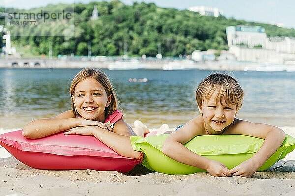 Glückliche Kinder entspannende Luftmatratzen Flussküste Sommerzeit