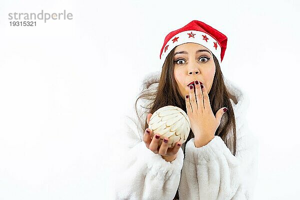 Brunette Mädchen an Weihnachten mit einem weißen Hintergrund  mit einem Weihnachtshut mit Sternen  überrascht und schüchtern Porträt wartet auf das Geschenk  Kopie Raum