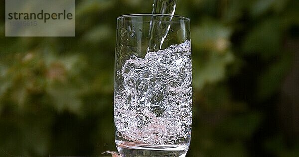 Wasser wird ins Glas gegossen