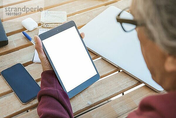Close up Senior Mann suchen digitale Tablette mit leeren weißen Bildschirm Holztisch