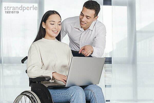 Junge Frau im Rollstuhl bei der Arbeit mit einem männlichen Kollegen