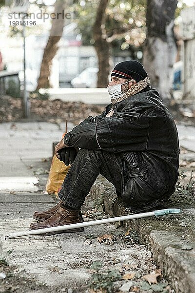 Seitenansicht Obdachloser Mann im Freien mit Stock medizinische Maske