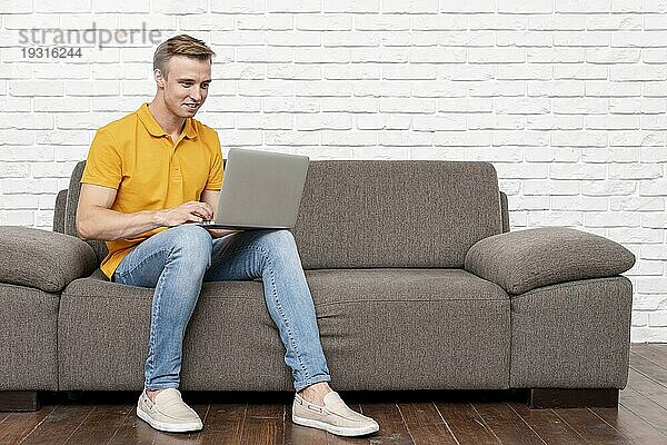 Vorderansicht Mann sitzend beim Überprüfen des Laptops