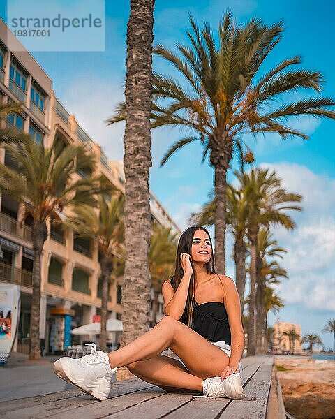 Sommerlicher Lebensstil  junge brünette Kaukasierin an der Mittelmeerküste  die auf einem Felsen am Meer in Torrevieja sitzt. Alicante  Spanien  Europa
