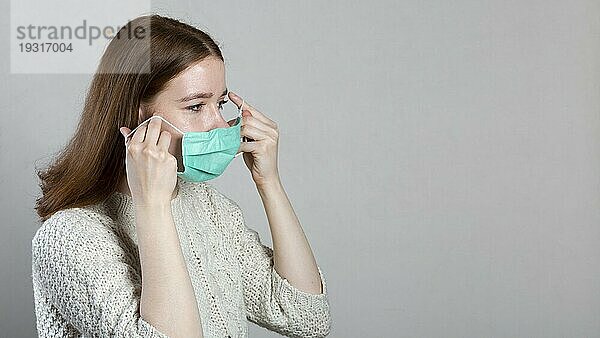 Seitenansicht Frau setzt medizinische Maske mit Kopierraum
