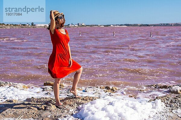 Mädchen mit rotem Kleid und Strohhut in der rosa Lagune von Torrevieja  Alicante. Gemeinschaft von Valencia. Spanien  Urlaub am Mittelmeer
