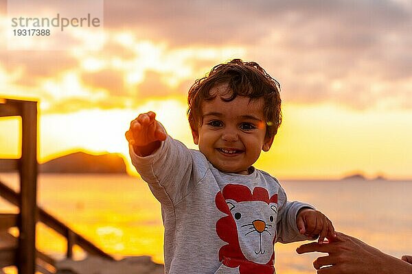 Lachender Junge bei Sonnenuntergang am Strand von Cala Comte auf der Insel Ibiza. Balearen