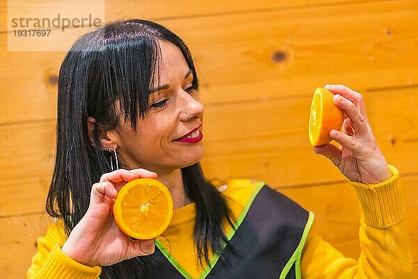 Spaß mit Orangen in der Hand eines brünetten kaukasischen Obstmädchens  das in einem Gemüseladen arbeitet