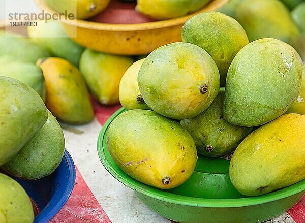 Ein Tisch mit einem Korb voller Mangos auf dem Straßenmarkt Selektiver Fokus