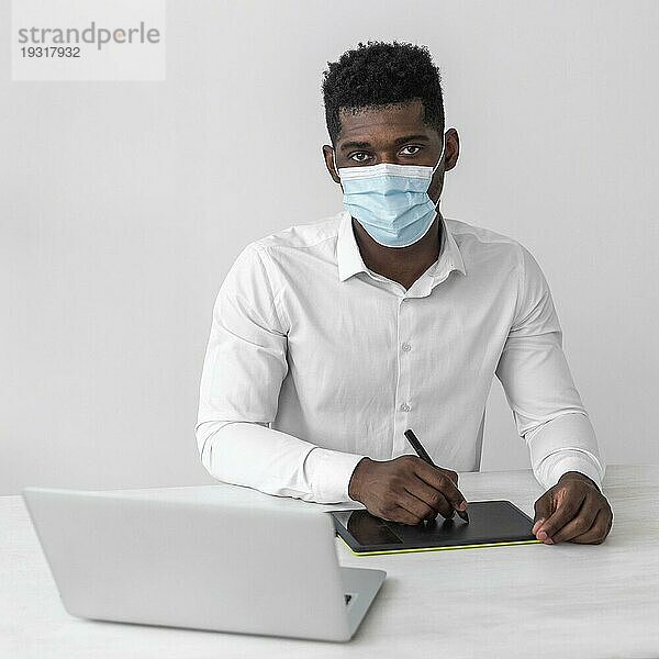 Afroamerikanischer Mann mit medizinischer Maske bei der Arbeit