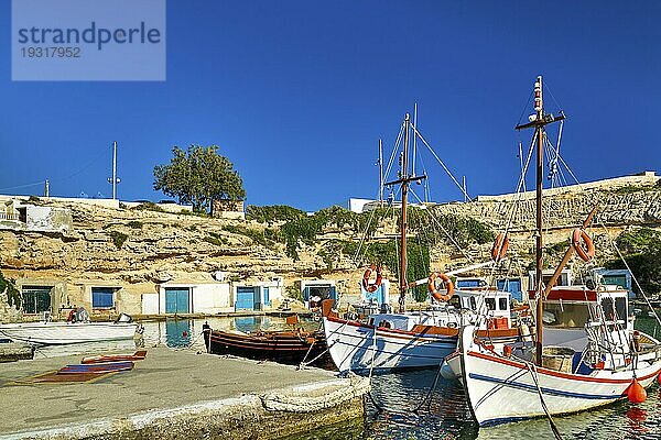 Schöne Aussicht auf bunte griechische Fischerboote vor Anker in einem kleinen Dorf. Sommertag Sonnenschein  Insel  Stadt  weiß getünchte Häuser  bunte Bootshäuser  mediterraner Lebensstil  Kalksteinhügel  Urlaub  Reiseziele. Milos  Griechenland  Europa