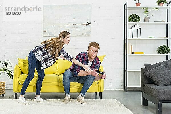 Junge Frau nimmt Joystick von seinem Freund beim Videospiel