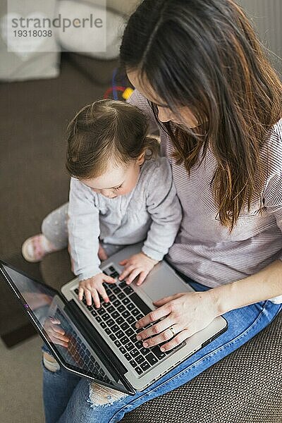 Draufsicht auf eine Mutter  die mit ihrem Kind am Laptop sitzt