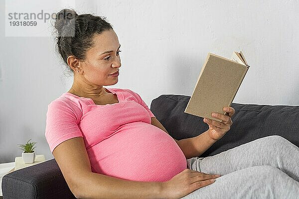 Seitenansicht schwangere Frau zu Hause lesen Couch