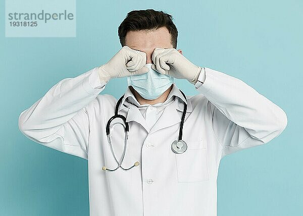 Vorderansicht Arzt mit medizinischer Maske  der sich die Augen reibt