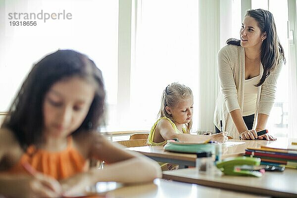 Lehrerin lehnt sich an einen Tisch und schaut weg