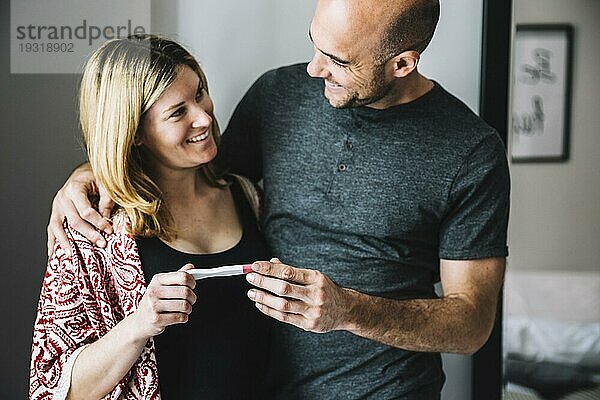 Glückliche Frau Ehemann sucht Schwangerschaftstest