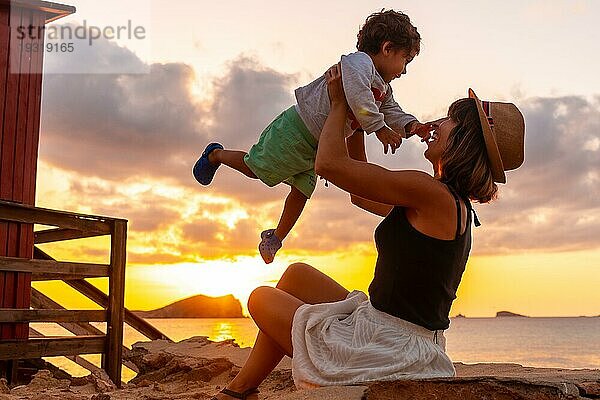 Eine Mutter vergnügt sich mit ihrem Sohn bei Sonnenuntergang am Strand von Cala Comte auf der Insel Ibiza. Balearen
