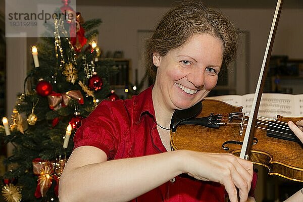 Frau musiziert auf einer Geige zu Weihnachten  woman is playing violin at christmas