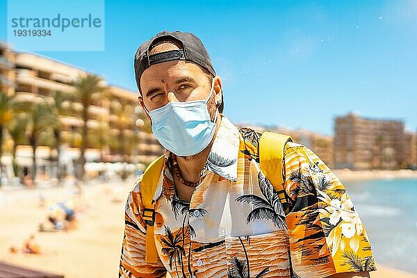 Ein junger Mann mit einer chirurgischen Touristenmaske am Strand von Cura in der Küstenstadt Torrevieja  Alicante  Valencianische Gemeinschaft. Spanien  Mittelmeer