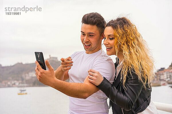 Lebensstil eines kaukasischen Paares beim Sightseeing im Urlaub  am Meer  das ein Foto macht und lächelt