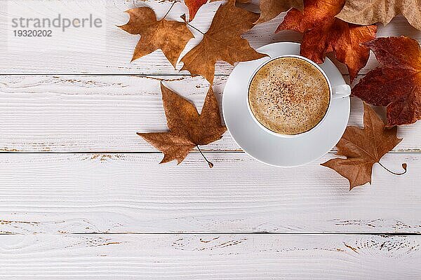 Heißer Kaffee Cappucino und Herbstblätter auf alten weißen hölzernen Hintergrund.saisonale entspannen Konzept