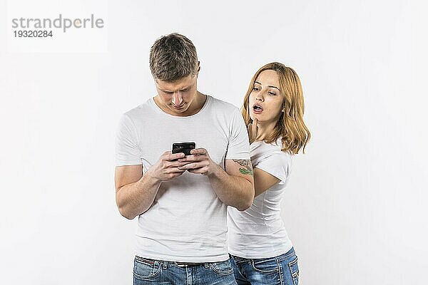 Junge Frau spioniert ihr Freund s Telefon gegen weißen Hintergrund