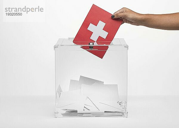 Person  die eine Karte mit der Schweizer Flagge in die Wahlurne steckt