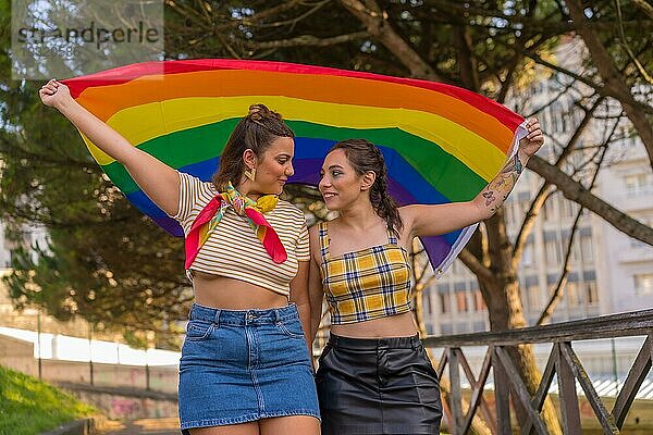 Eine Nahaufnahme von zwei jungen kaukasischen Frauen halten LGBT Stolz Flagge im Freien