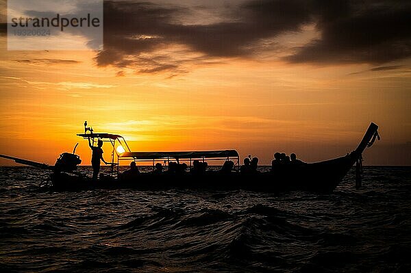 Sonnenuntergang hinter einem Longtailboot mit Passagieren in der Andamanensee  Südthailand in der Nähe von Ko Phi Phi