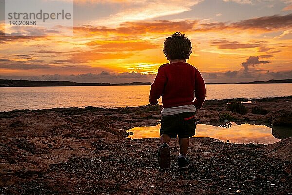 Sonnenuntergang in Ibiza im Urlaub  ein Kind läuft und lacht am Meer in San Antonio Abad