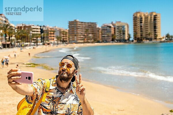 Ein junger Tourist macht ein Selfie am Playa del Cura in der Küstenstadt Torrevieja  Alicante  Valencianische Gemeinschaft. Spanien  Mittelmeer