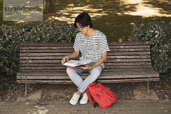 Asiatischer Teenager Mann mit Lehrbuch Bank