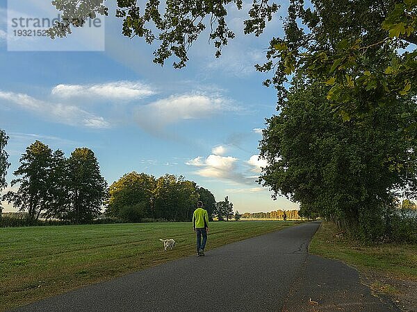 Spaziergänger mit Hund am Morgen  weite Auenlandschaft und Wiesen  Schlepzig  Spreewald  Brandenburg  Deutschland  Europa