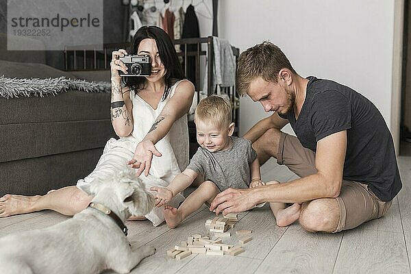 Junge Frau nimmt Hund mit Kamera sitzt in der Nähe seines Sohnes Mann spielen zusammen