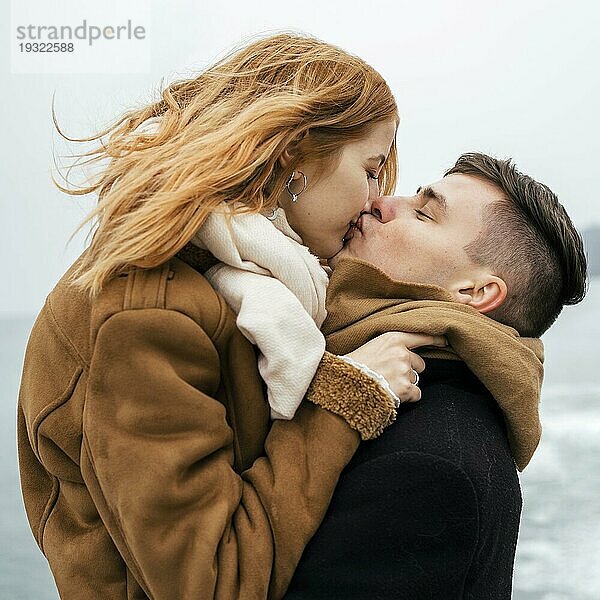 Seitenansicht Paar am See im Winter küssend
