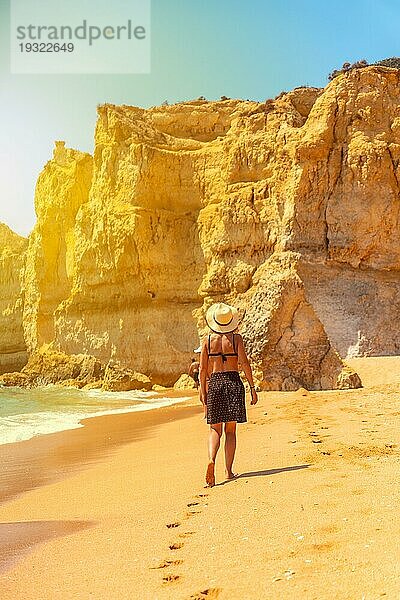 Eine Frau mit einem Hut bei Sonnenuntergang am Strand von Praia da Coelha  Algarve  Albufeira. Portugal