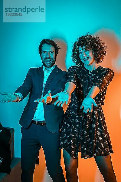 Party Lifestyle  ein sehr glückliches Paar tanzt auf einer Party mit blauen und orangenen Lichtern