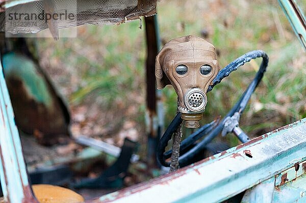 Alte sowjetische Gasmaske auf dem Lenkrad eines liegengebliebenen Autos drapiert