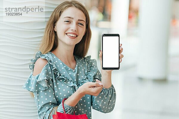Glückliches Mädchen zeigt ihr Telefon