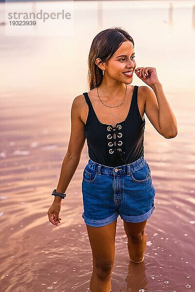 Eine junge brünette Kaukasierin  die im Sommer in der rosa Lagune von Torrevieja Urlaub macht  trägt Jeans und ein schwarzes TShirt Alicante. Spanien