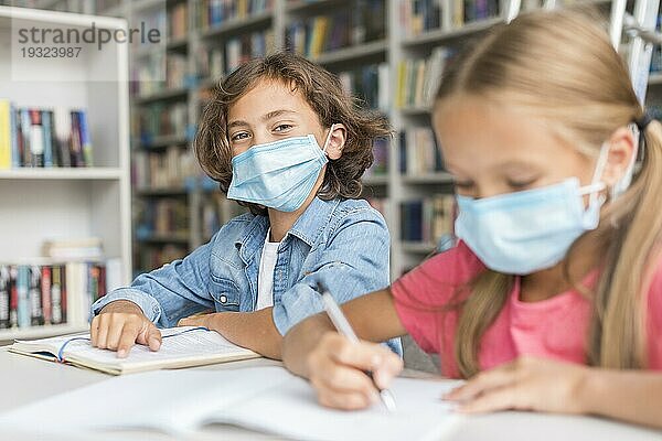 Kinder machen Hausaufgaben und tragen dabei medizinische Masken