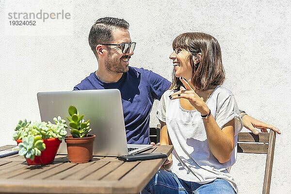 Ein Ehepaar  das zu Hause eingesperrt ist  führt einen Videogespräch mit einigen Freunden mit dem Computer  auf der Terrasse ihres Hauses mit einem weißen Hintergrund  die an einem Tisch sitzen. Viel Spaß beim Videoanruf