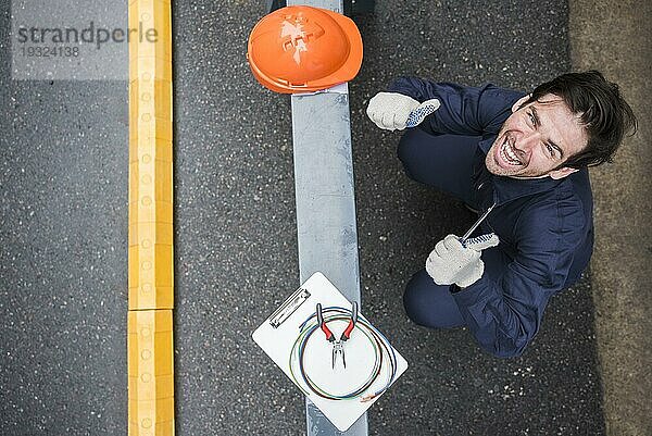 Hoher Winkel Blick glücklich männlichen Elektriker zeigt Daumen nach oben Arbeitsplatz